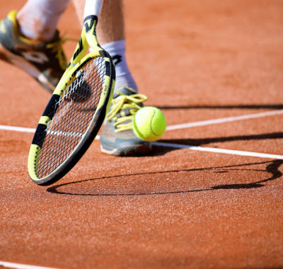 A close-up of a tennis player's foot and racquet hitting a shot at Happy Acres RV Park in Pueblo, Colorado.