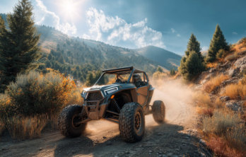 A side by side on a dusty trail with green trees in the foreground and mountains in the background and the sun showing in a bright blue sky near happy acres RV Park in Pueblo Colorado
